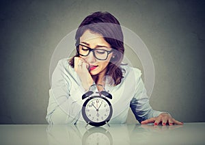 Anxious businesswoman looking nervously at alarm clock