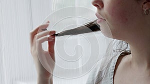 Anxious Caucasian woman curls lock of hair on her finger. Close-up of hand and face. Concept of psychological disorder