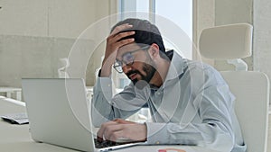 Anxious depressed Indian Arabian man stressed businessman working laptop in office distant job male tired muslim