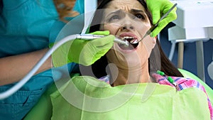 Anxious female sitting in dentistry chair after procedure of caries removal