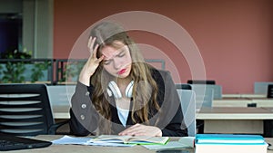 Anxious girl feeling tired while studying at school. College student suffering from headache in classroom. Troubled and