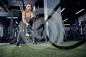 Anxious lady slamming the battle ropes on the floor
