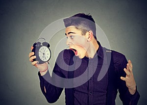Anxious man looking at alarm clock. Time pressure concept
