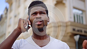 Anxious man talking mobile in city. Afro guy having phone conversation on street