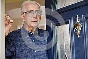 Anxious Senior Man At Home Looking Out Of Front Door