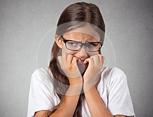 Anxious stressed teenager girl with eyeglasses biting fingernails