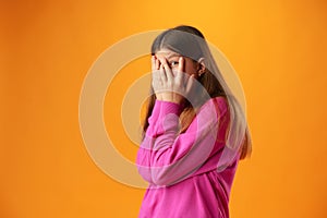 Anxious teen girl looking scared or worried on yellow background