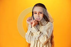 Anxious teen girl looking scared or worried on yellow background