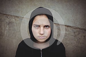 Anxious teenage girl in black hooded jacket standing at school