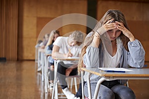 Anxious Teenage Student Sitting Examination In School Hall photo