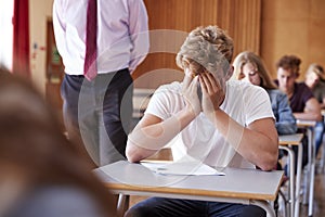 Anxious Teenage Student Sitting Examination In School Hall photo