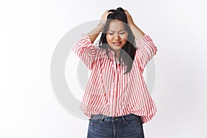 Anxious and troubled worried cute female staff in striped blouse feeling nervous and perplexed grab head with hands