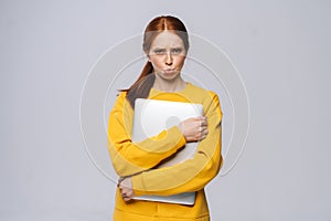 Anxious upset young business woman or student holding laptop computer and looking at camera