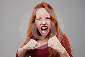 Anxious woman with red hair holding two fists