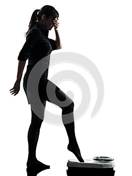 Anxious woman standing on weight scale silhouette