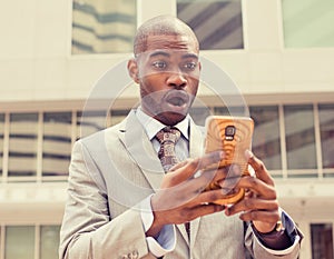 Anxious young business man looking at phone seeing bad news