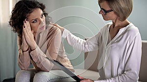 Anxious young female patient looking with hope at psychotherapist, real help