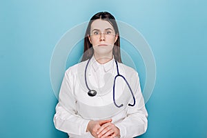 Anxious young woman doctor feels mental burnout at work, looking unhappy at camera, wears coat, stethoscope