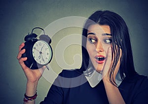 Anxious young woman looking at alarm clock. Time pressure concept