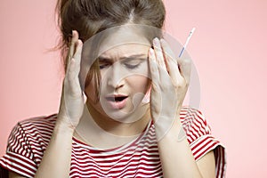 Anxious young woman looking at one-off medical pregnancy test on pink studio background, disappointed girl cry in stress, concept
