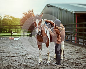 Any day is good day for a ride. a teenage girl preparing to ride her pony on a farm.