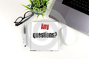 ANY QUESTIONS text on notebook with laptop, mouse and pen