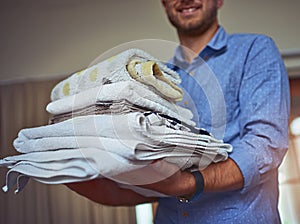 Anyone call for clean towels. Cropped shot of a young man holding a load of freshly folded clean laundry.