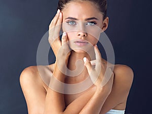 Anyone can be beautiful as long as they keep believing. Studio shot of an attractive young woman posing and touching her