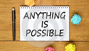 Anything is possible symbol. Concept words Anything is possible on beautiful white note. Beautiful wooden background. Black pen.