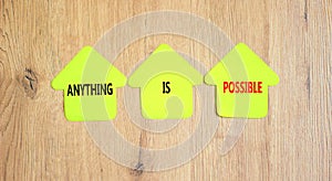 Anything is possible symbol. Concept words Anything is possible on beautiful yellow paper houses. Beautiful wooden table wooden