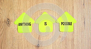 Anything is possible symbol. Concept words Anything is possible on beautiful yellow paper houses. Beautiful wooden table wooden