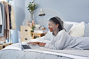 Anytime is a time to blog. an attractive young woman using a laptop while chilling on her bed in her bedroom at home.