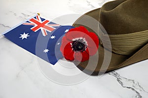 Anzac army slouch hat with Australian Flag and Poppy on stone background