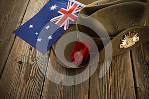 Anzac army slouch hat with Australian Flag and Poppy on wooden background