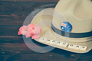 Anzac army slouch hat with red flower on vintage wood background