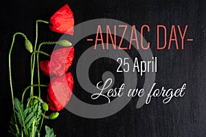 Anzac day. Greeting card with the inscription and poppy flowers on a black background. Flat lay, top view photo