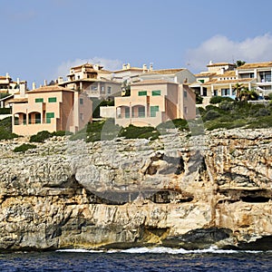 Apartment blocks with holiday apartments on the steep rocky coast of Mallorca seen from the sea