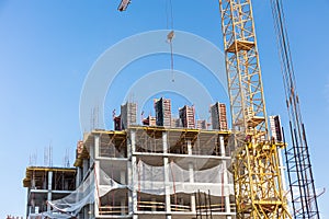 Apartment building construction site with crane against blue sky