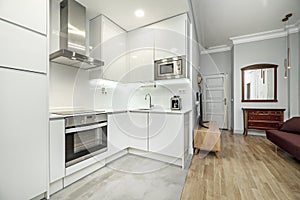 Apartment with fitted kitchen open to living room with oak parquet floors, sideboard with mirror and wine-colored sofa