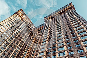 apartment house building skyscraper with large windows and balconies against a blue sky with clouds