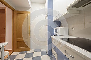 apartment kitchen with white and blue cabinets to match the tiles and oak wood door