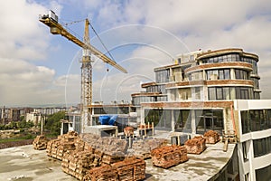 Apartment or office tall building under construction. Brick walls, glass windows, scaffolding and concrete support pillars. Tower