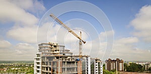 Apartment or office tall building under construction. Brick walls, glass windows, scaffolding and concrete support pillars. Tower