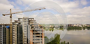 Apartment or office tall building under construction. Brick walls, glass windows, scaffolding and concrete support pillars. Tower