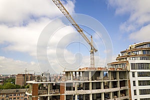 Apartment or office tall building under construction. Brick walls, glass windows, scaffolding and concrete support pillars. Tower