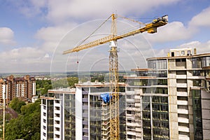 Apartment or office tall building under construction. Brick walls, glass windows, scaffolding and concrete support pillars. Tower