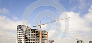 Apartment or office tall building under construction. Brick walls, glass windows, scaffolding and concrete support pillars. Tower