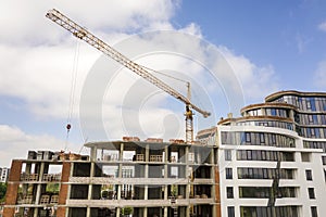 Apartment or office tall building under construction. Brick walls, glass windows, scaffolding and concrete support pillars. Tower