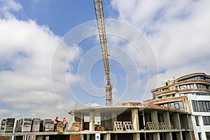 Apartment or office tall building under construction. Brick walls, glass windows, scaffolding and concrete support pillars. Tower