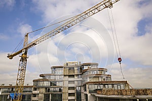 Apartment or office tall building under construction. Brick walls, glass windows, scaffolding and concrete support pillars. Tower